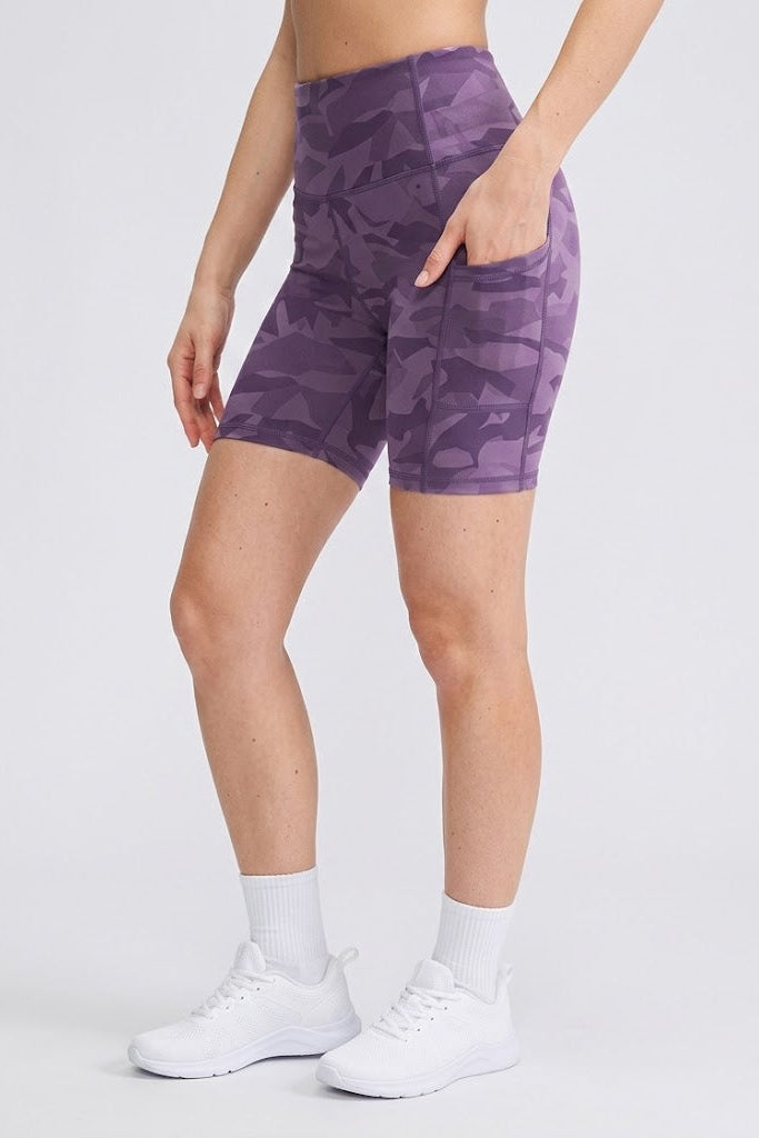 Person wearing purple camouflage shorts on a white background