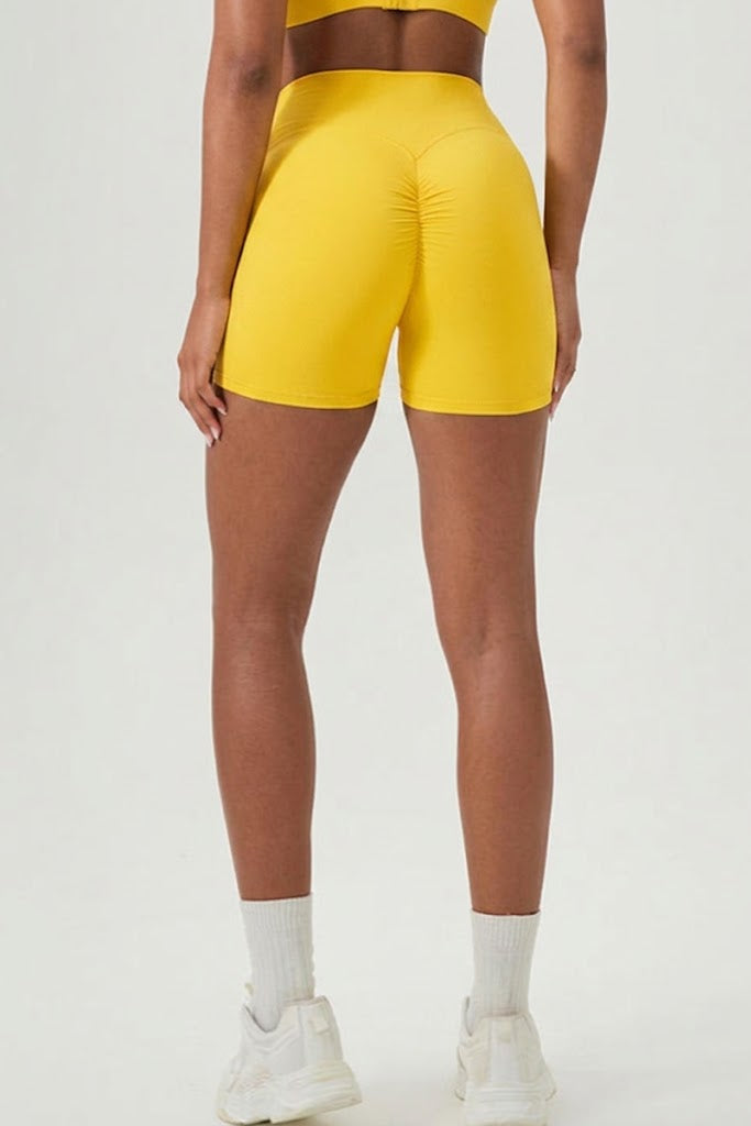 Person wearing yellow athletic shorts on a white background