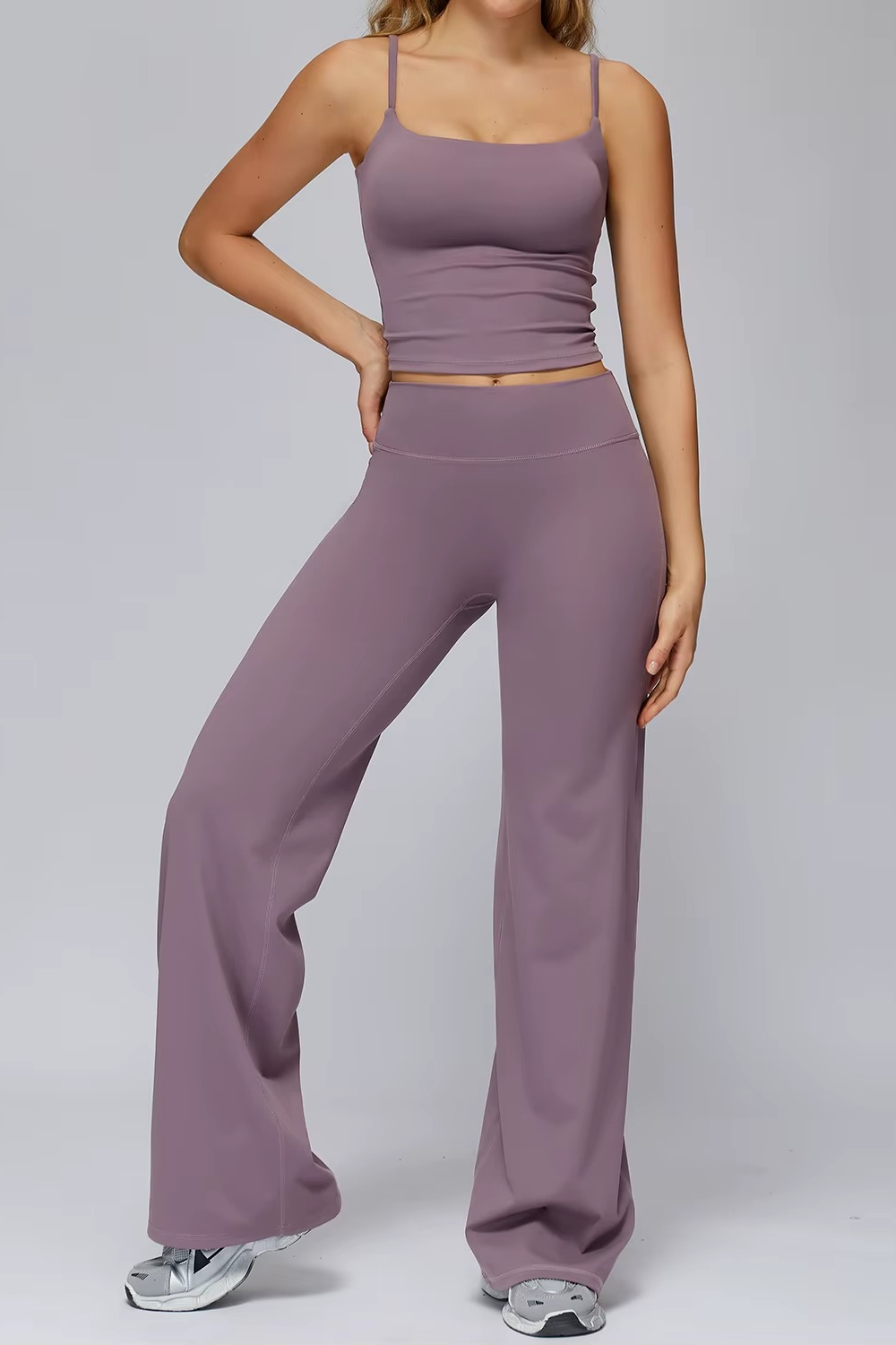Person wearing a matching purple tank top and pants set on a gray background