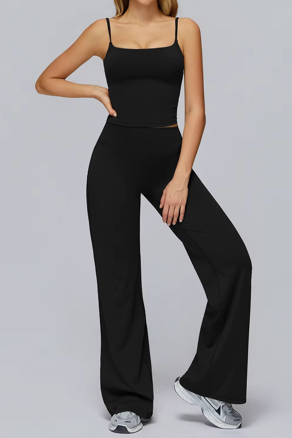Person wearing a black outfit with wide-leg pants on a gray background