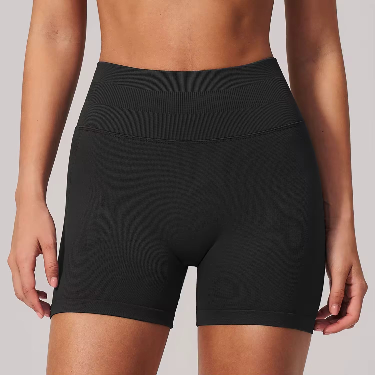 Black athletic shorts worn by a person on a plain background