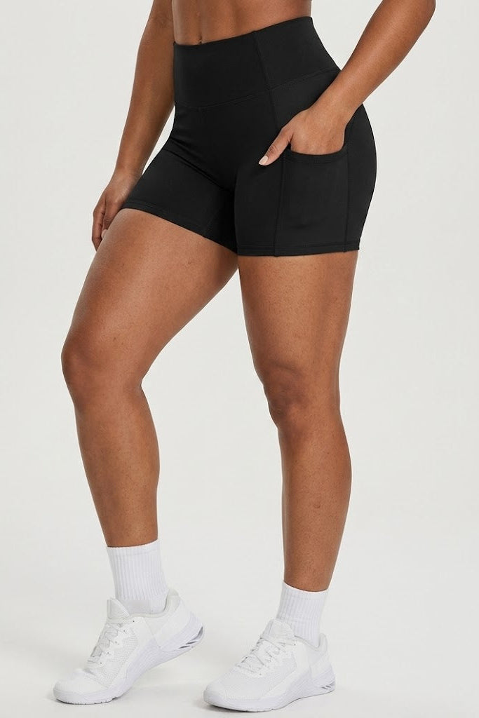 Person wearing black athletic shorts and white sneakers on a light gray background